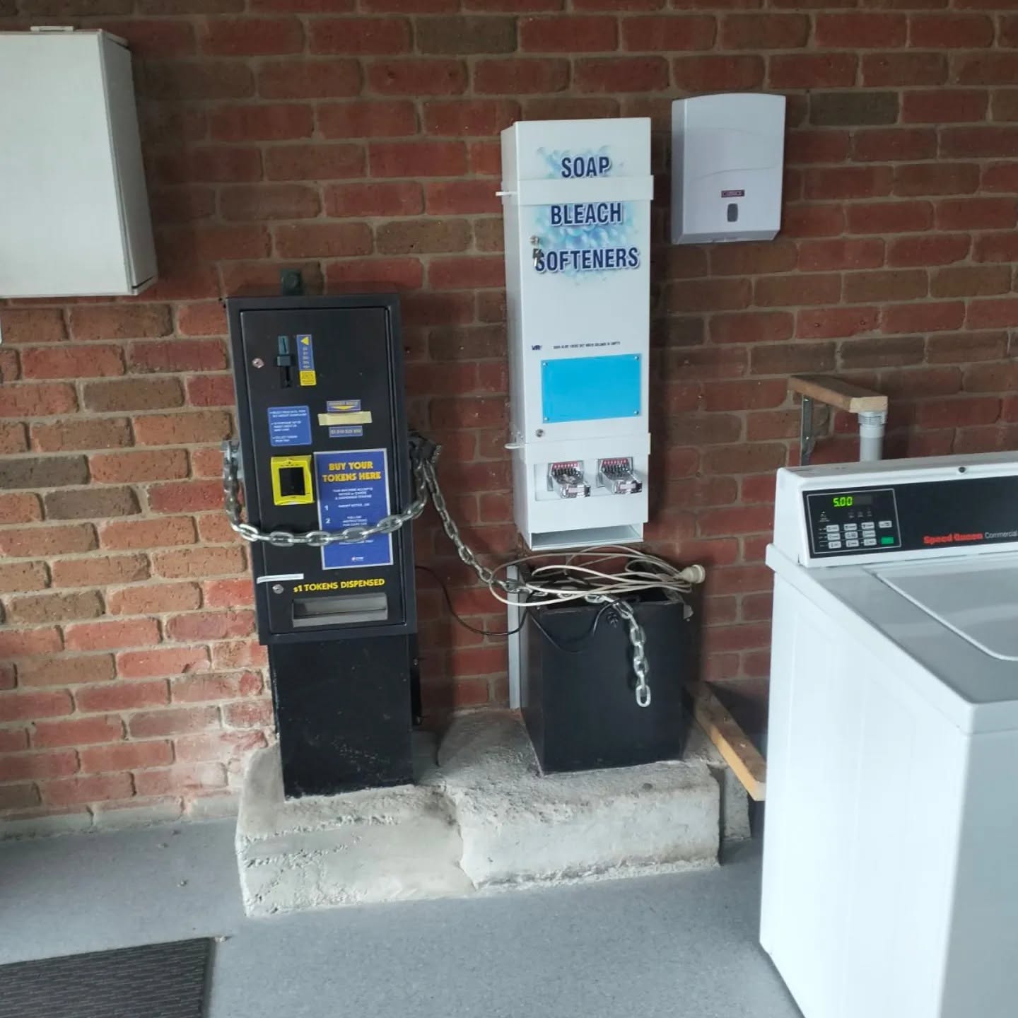Token machine and soap, bleach and softener dispenser on a brick wall